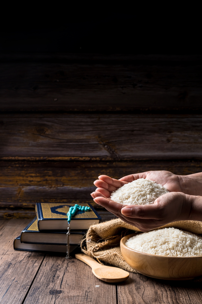 Hands,Holding,A,Wooden,Bowl,Of,Rice,Grains,For,Zakat,